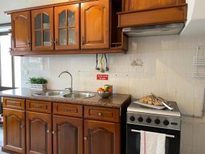 a kitchen with wooden cabinets and a sink and a stove at Private Villa 4 BR&patio - 3 mins from Beach&Surf in Baleal