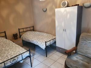 a room with two beds and a refrigerator and a chair at Appartement F1 rez de chausser BG N°2 in Bains-les-Bains