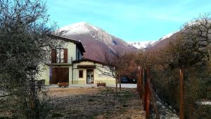 a house with a fence in front of a mountain at B&B Fonte Vena in Norcia