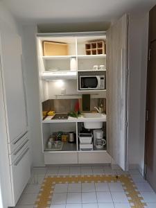 a kitchen with white cabinets and a microwave at MANGANAO STUDIO in Saint-François