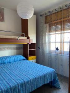 a bedroom with a bed with a blue comforter and a window at Casa vacanze Brezza di mare in Tortora