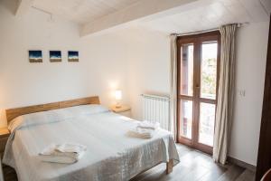 una camera da letto bianca con un letto e una finestra di Alghero in bicicletta ad Alghero