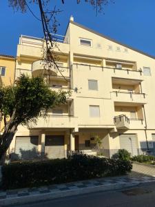 un edificio de apartamentos con un árbol delante de él en Casa vacanze Brezza di mare, en Tortora