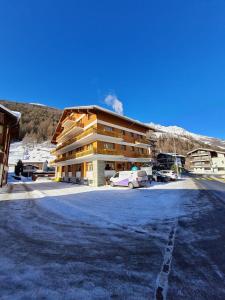 a large building with cars parked in a parking lot at Hotel Krone - only Bed & Breakfast in Saas-Grund