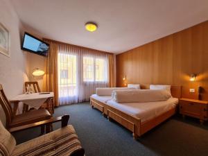 una camera d'albergo con due letti e una televisione di Hotel Krone - only Bed & Breakfast a Saas-Grund