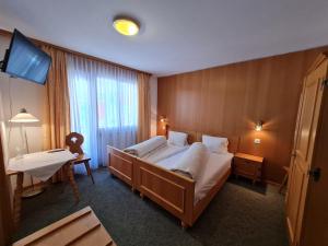 una camera d'albergo con un grande letto e una TV di Hotel Krone - only Bed & Breakfast a Saas-Grund