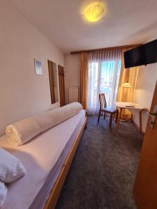 a hotel room with two beds and a desk at Hotel Krone - only Bed & Breakfast in Saas-Grund