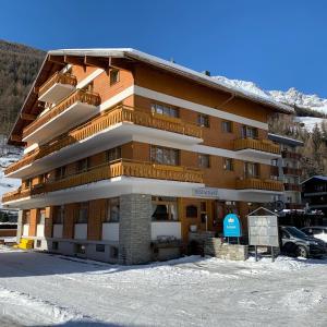 a large wooden building with snow in front of it at Hotel Krone - only Bed & Breakfast in Saas-Grund