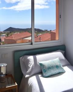 Bett in einem Zimmer mit einem großen Fenster in der Unterkunft Casa Ninive in Fuencaliente de la Palma