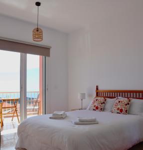 a bedroom with a large white bed with a balcony at Casa Ninive in Fuencaliente de la Palma