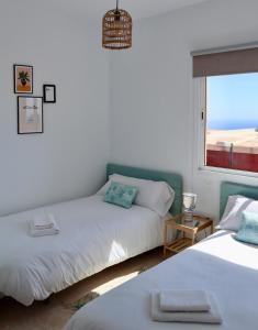 a bedroom with two beds and a window with the ocean at Casa Ninive in Fuencaliente de la Palma