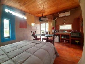 a bedroom with a bed and a table and a kitchen at ECOCABAÑAS CERRO ARKO in Mendoza