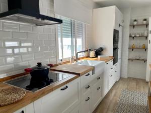una cocina con armarios blancos y fregadero en La Higuera, en Rota