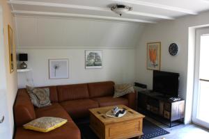 ein Wohnzimmer mit einem braunen Sofa und einem TV in der Unterkunft Schönes Ferienhaus in Oostmahorn (176) in Anjum