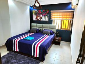 1 dormitorio con 1 cama con manta azul y roja en Jayé, appart chic à 200m de la plage+ vue sur mer, en Cotonou