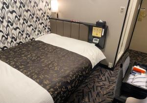 a hotel room with a bed and a clock on the wall at APA Hotel Hachioji Eki Kita in Hachioji