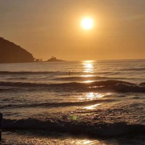 uma pessoa a surfar no oceano ao pôr-do-sol em Suíte Luxo Refúgio das Ostras no Guarujá