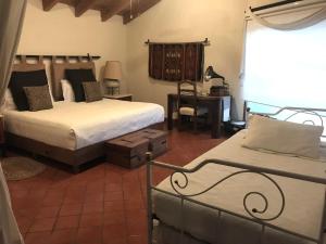 a bedroom with two beds and a desk and a window at Finca Las Palmas in Malinalco