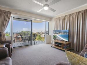 a living room with a television and a balcony at Cheltenham Apartments Unit 11 40 King St in Caloundra
