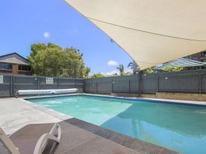 a swimming pool with an umbrella and a fence at Cheltenham Apartments Unit 11 40 King St in Caloundra