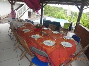 a long table with chairs and plates and food on it at Maison Jean in Le Gosier