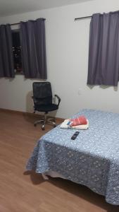 a bedroom with a bed and a chair and window at Quarto 201 in Juiz de Fora