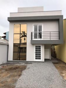 a white house with a balcony on top of it at Novo Lar Garopaba1 in Garopaba
