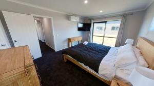 een slaapkamer met een bed en een groot raam bij Solar on Snowmass Red Door in Ohakune
