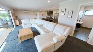 sala de estar con sofá blanco y mesa en Ohakune Solar on Snowmass, en Ohakune
