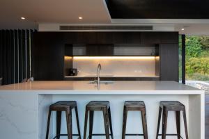a kitchen with a white counter and stools at The Hill Residence by Sotheby's Luxury Rental Homes in Queenstown +21 photos