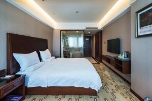 a bedroom with a large bed and a television at Sun Moon Lake Hotel Dalian大连火车站店 in Dalian