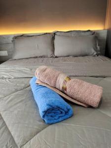a blanket and towel on a white bed at Urban360 Pool view stylist with android Tv in Batu Caves
