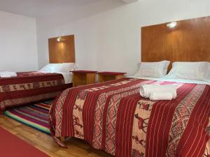 two beds in a hotel room with towels on them at Hotel Wiñay Pacha Inn in Puno