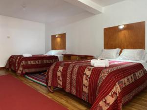 Habitación de hotel con 2 camas y mantas rojas en Hotel Wiñay Pacha Inn, en Puno
