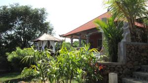 The Raja Singha Boutique Resort Bali في لوفينا: منزل بحائط حجري وبعض النباتات