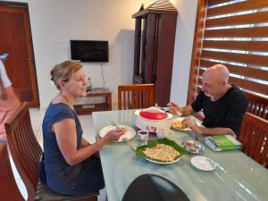 Riverlap homestay في Nīleshwar: يجلس رجل وامرأة على طاولة لتناول الطعام