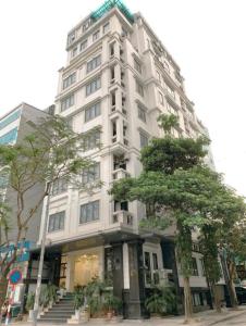 Biały budynek z drzewem przed nim w obiekcie Poonsa Duy Tan Hotel and Serviced Apartment w mieście Hanoi