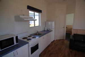a kitchen with a stove and a sink and a microwave at Bicheno East Coast Holiday Park in Bicheno