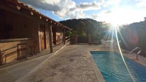 a patio with a swimming pool and a house at Pousada Casa do Lago in Águas da Prata