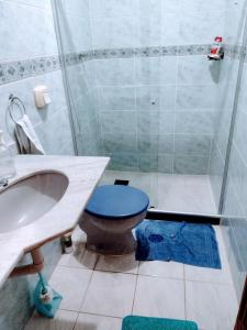 uma casa de banho com um WC azul e um chuveiro em Temporada em Cabo Frio em Cabo Frio
