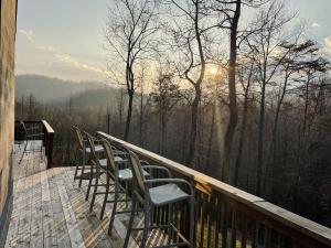 a deck with chairs and the sun in the trees at Windrock Retreat in Oliver Springs