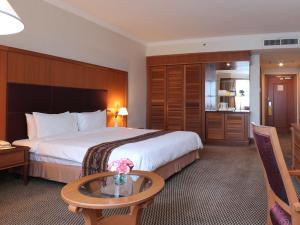 Imperial Hotel Miri في ميري: غرفة فندقية بسرير كبير وطاولة