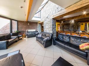 ein Wohnzimmer mit Ledersofas und einer Steinwand in der Unterkunft Stone Cottage with Sauna Jacuzzi a 5 min drive from the cave of Lorette in Rochefort in Han-sur-Lesse