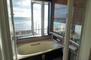 La salle de bains est pourvue d'une baignoire et d'une fenêtre donnant sur l'océan. dans l'établissement Sinori205, à Hakodate