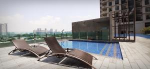 two chairs and a swimming pool on top of a building at Sunway Paradise Home Staycation PH2120 SELF CHECK IN OUT in Subang Jaya
