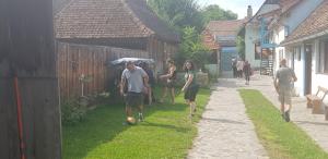 um grupo de pessoas andando por uma rua com um guarda-chuva em Pensiunea Ramona em Viscri
