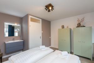 a bathroom with two beds and a sink in it at Welcome in - Duinweg 18 in Zoutelande
