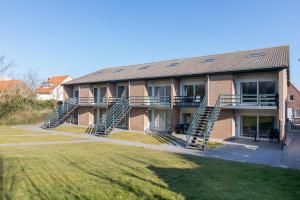a brick building with stairs in front of a yard at Welcome in - Duinweg 18 in Zoutelande