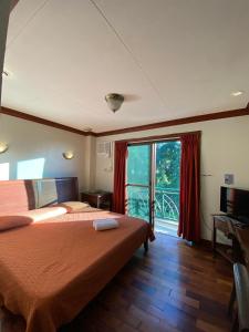 タガイタイにあるMC Mountain Homeのベッドとバルコニー付きのホテルルーム