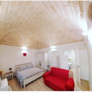 a bedroom with a bed and a red couch at Dimora Dei Gelsi in Polignano a Mare